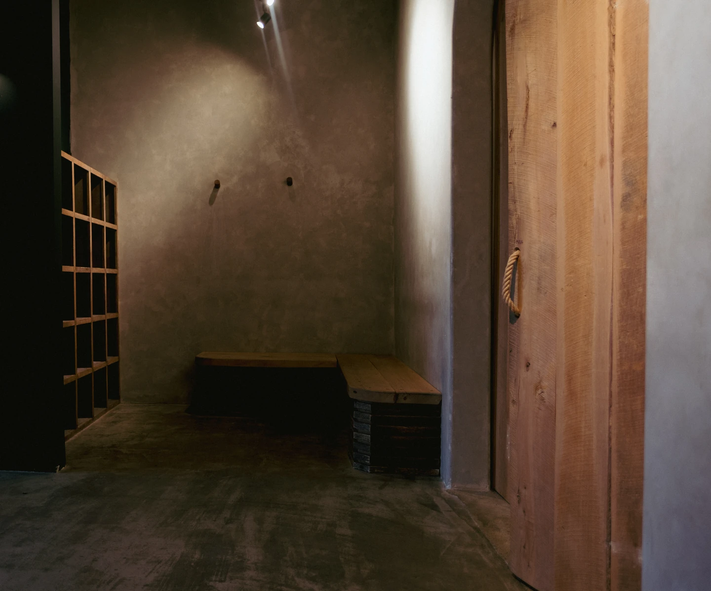 Warm limewashed walls, reclaimed wood benches, cubbies, and a wooden studio door with a rope handle.