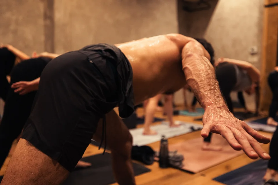 An outstretched hand and arm lead a close view of bodies moving through practice.