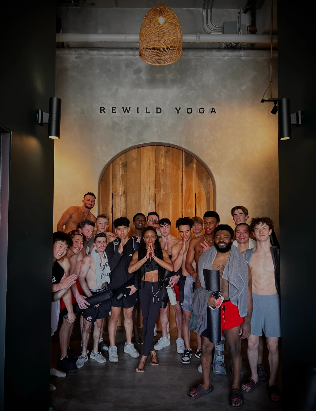 OSU gymnasts gathered beneath the REWILD YOGA name in front of the studio’s arched wooden doors.